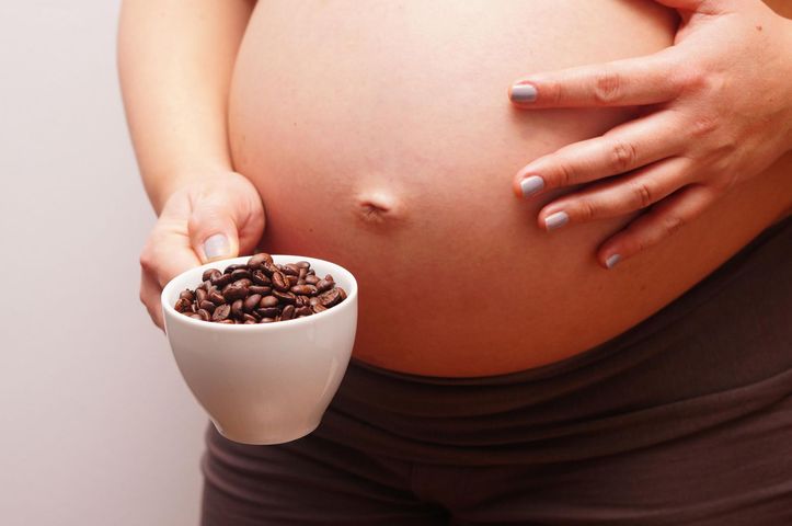 Kobieta w ciąży trzyma kawę