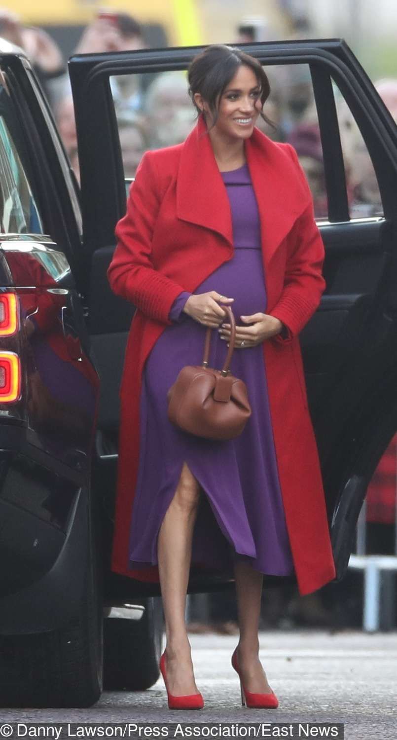 Meghan Markle z ciążowym brzuszkiem w czerwonym płaszczu