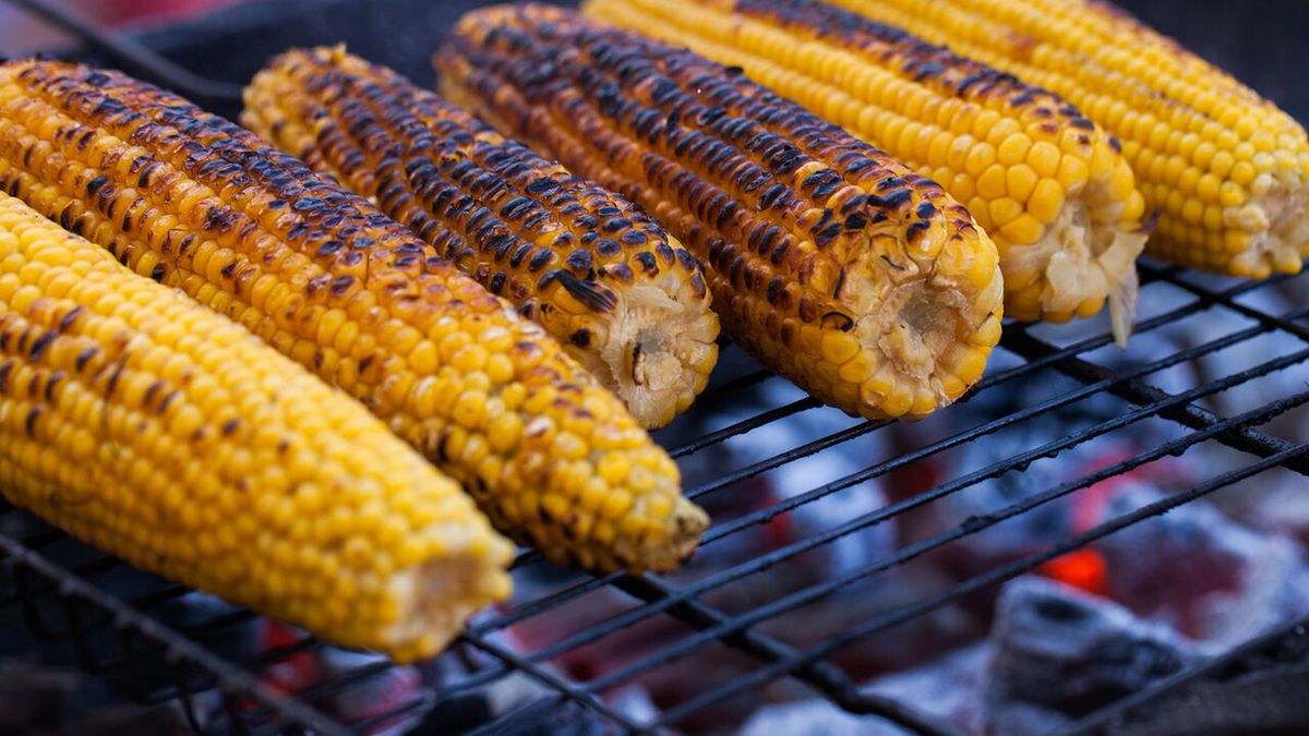 Posmaruj kukurydzę oliwą z oliwek, przypraw solą i pieprzem, a następnie umieść ją na grillu.