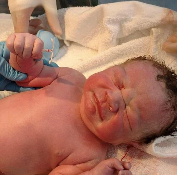 Nowonarodzone dziecko ze spiralą w dłoni