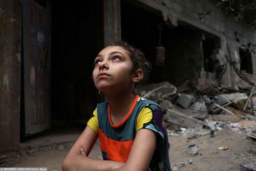 Dziewczynka patrząca na swój zniszczony dom