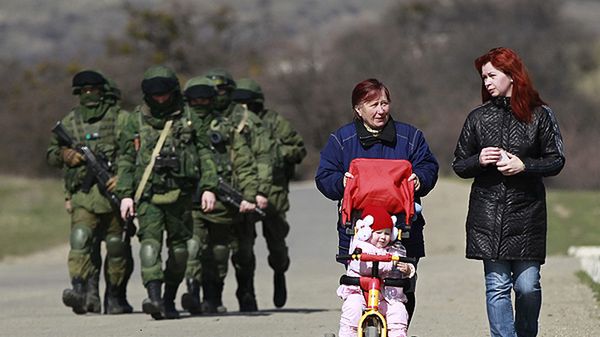 Mieszkanki Krymu na spacerze. W tle maszerujący żołnierze