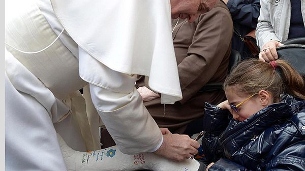 Papież Franciszek składa podpis na gipsie