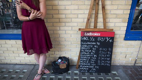 Kobieta prezentuje przed londyńskim szpitalem St Mary's tablicę z brytyjskiego zakładu bukmacherskiego. Na tablicy są m.in. prawdopodobne imiona królewskiego potomka.