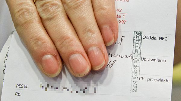 Farmaceutka prezentuje receptę z pieczątką "refundacja do decyzji NFZ"
