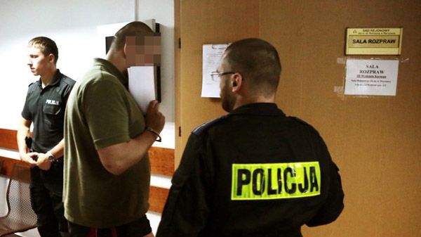 Policjanci prowadzą na salę rozpraw zatrzymanego Rosjanina