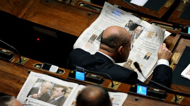 Włoscy deputowani z gazetami na sali obrad parlamentu