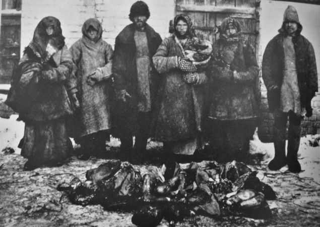 Rosyjscy chłopi podczas wielkiego głodu na początku lat 20., podczas którego dochodziło do licznych aktów kanibalizmu. Na ziemi leżą szczątki zjedzonych przez nich ludzi, ok. 1921-1922 r. 