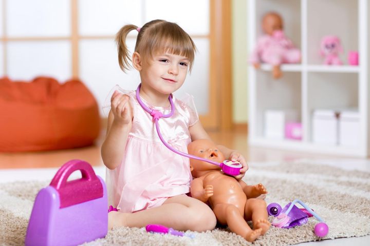 Dziewczynka bawi się z lalką w lekarza.