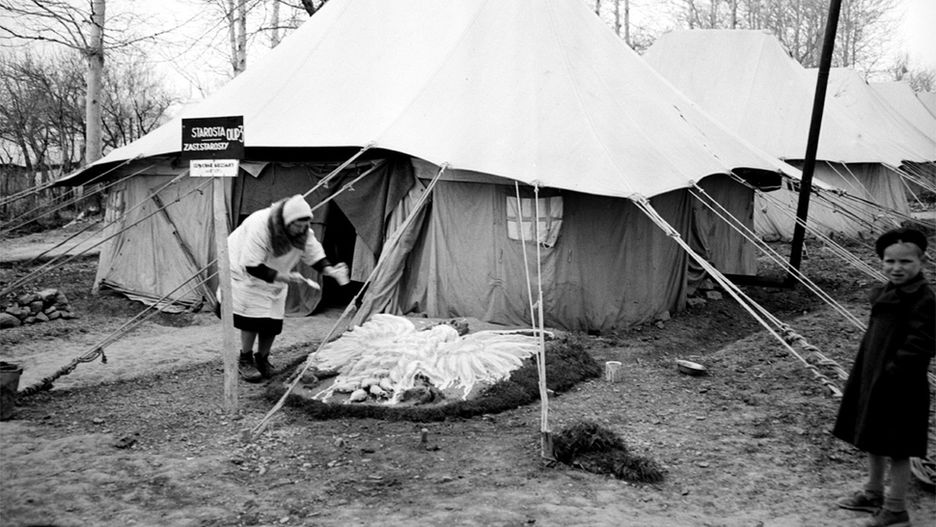 Polka maluje białego orła przed namiotem w obozie dla Polaków w Iranie, prowadzonym przez Czerwony Krzyż. Rok 1943