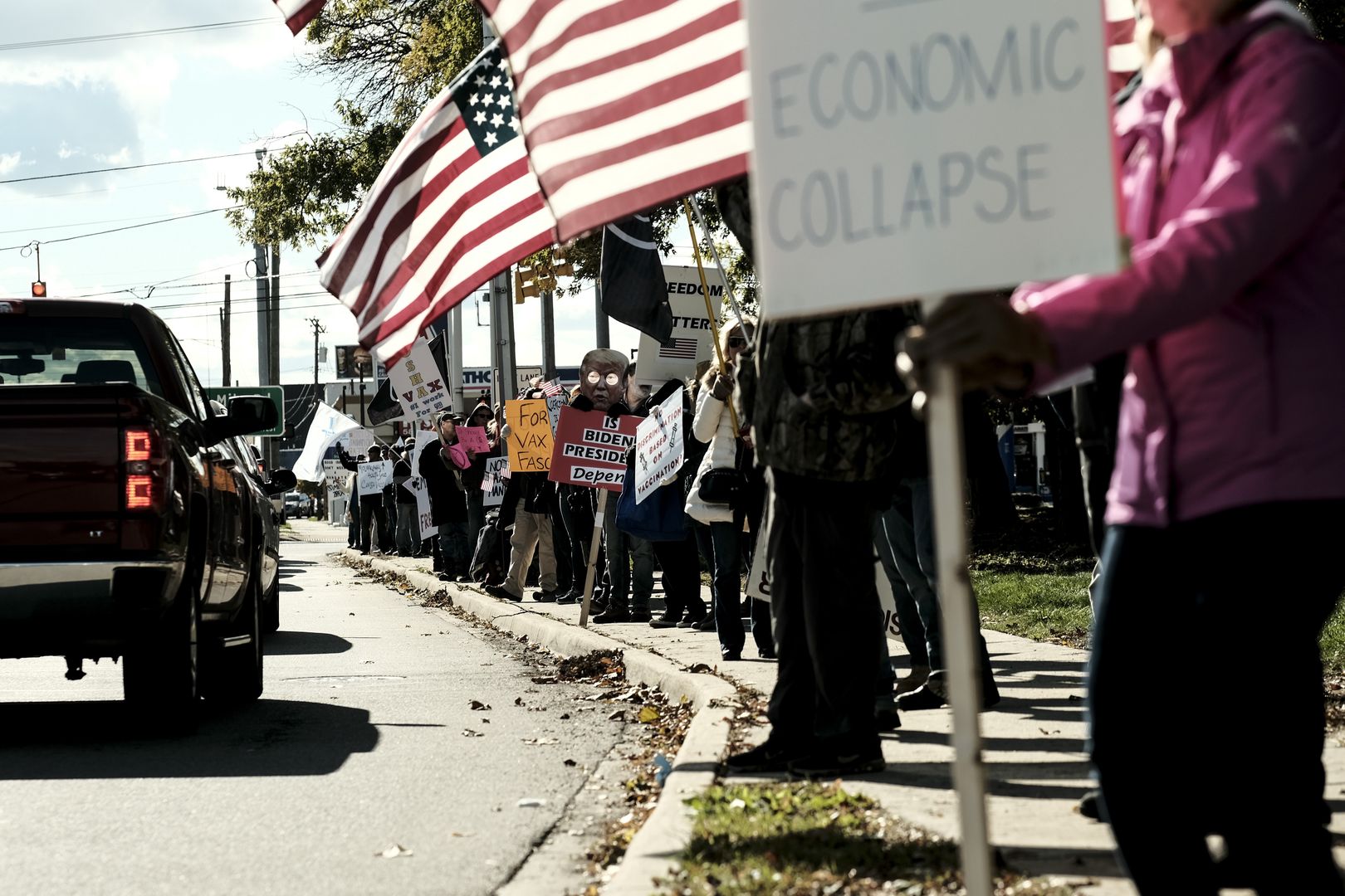 Demonstrators hold signs and wave American flags during a protest against Covid-19 mandates outside the General Motors (GM) Tech Center in Warren, Michigan, U.S., on Wednesday, Nov. 3, 2021. GM ordered its U.S. salaried staff to report their vaccination status, though the requirement doesnt apply to factory employees represented by the United Auto Workers. Photographer: Matthew Hatcher/Bloomberg via Getty Images