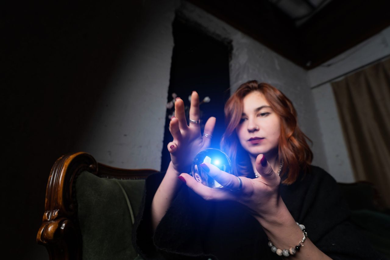Woman in black suit holding crystal ball in her hands