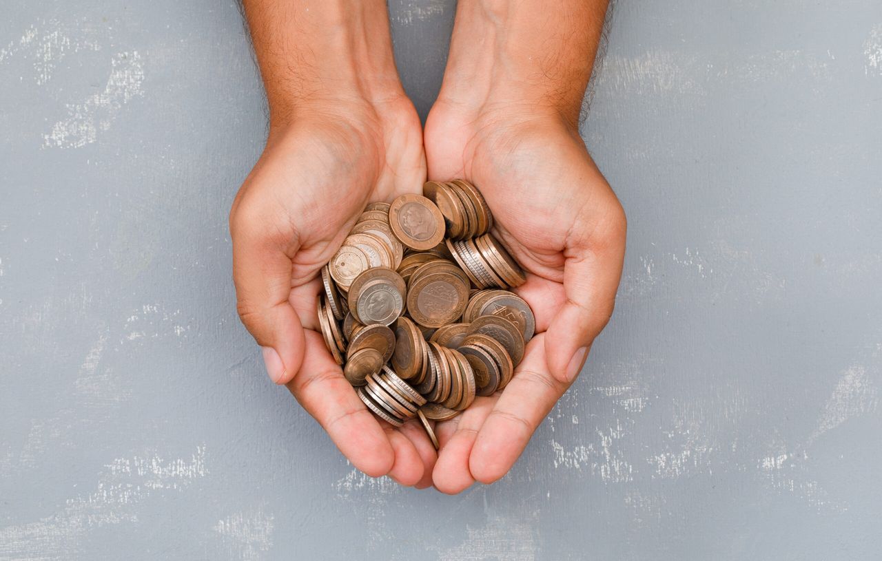 Monetary concept on plaster background flat lay. man holding coins in palm.