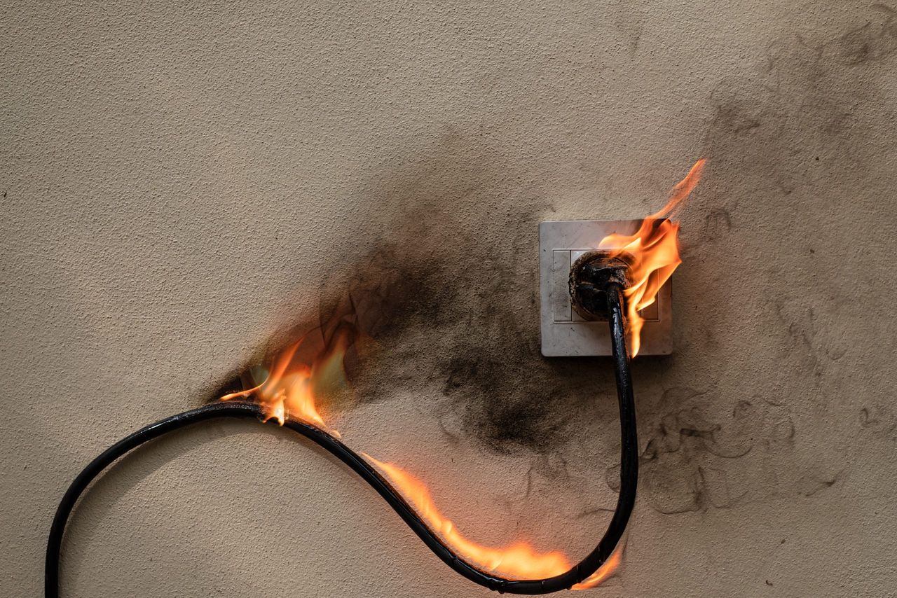 On fire electric wire plug Receptacle on the concrete wall exposed concrete background with copy space