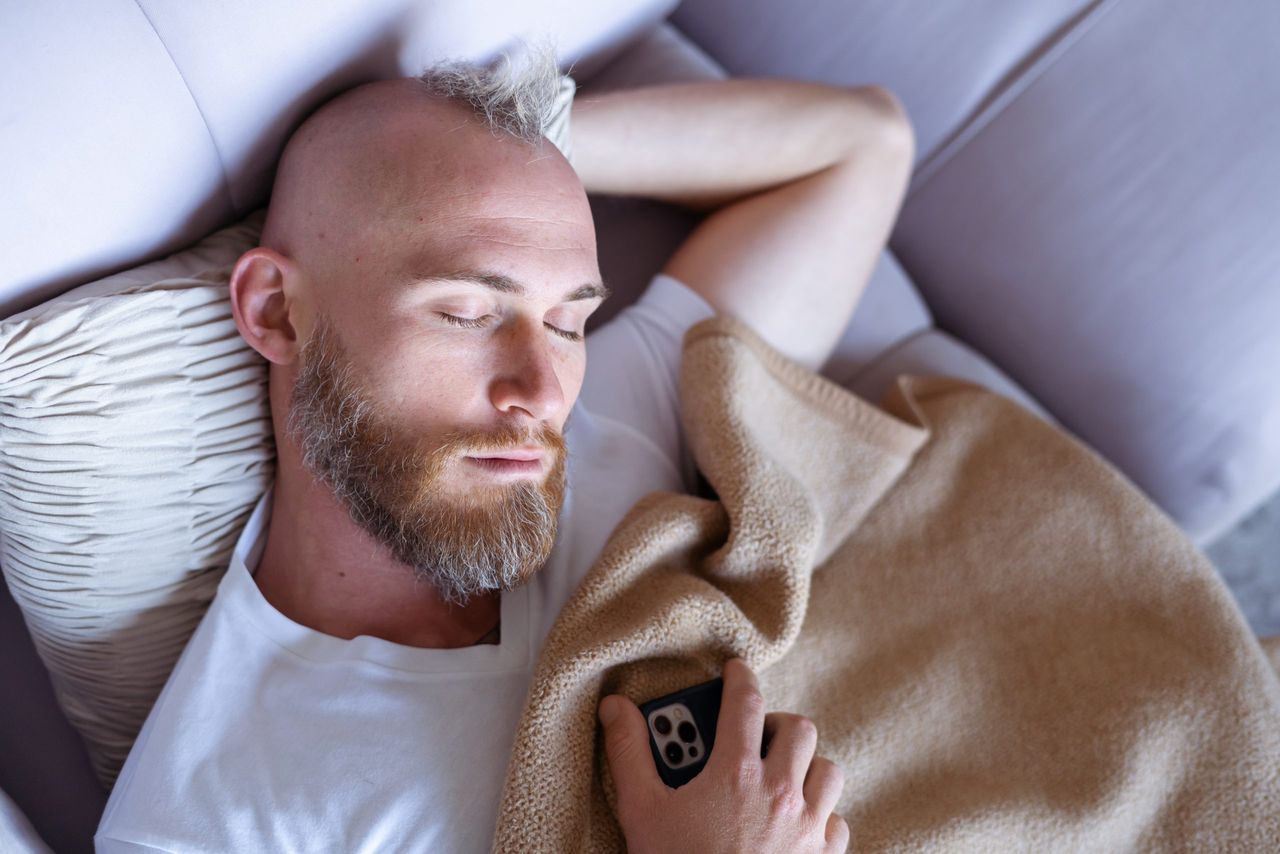 Young man at home fell asleep on the couch with a mobile phone