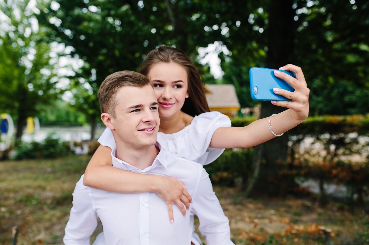 Beautiful young couple relaxing in the park and makes selfie