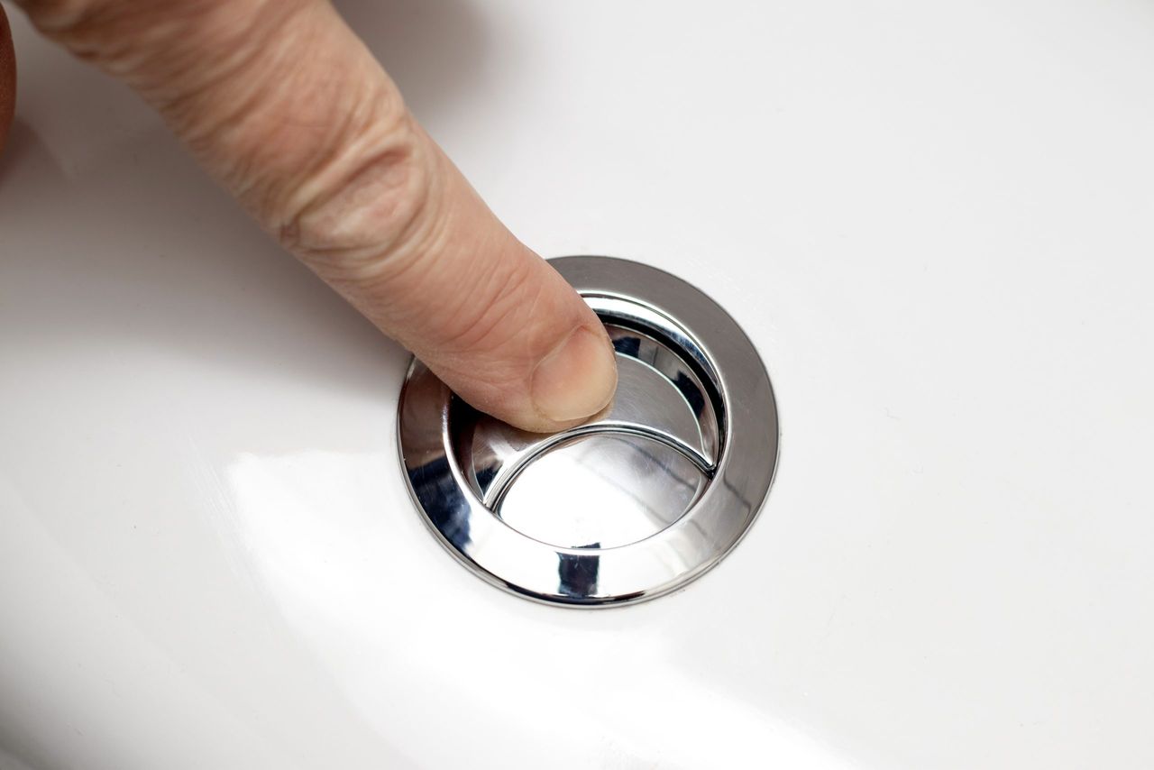 A man presses his finger on the flush button in the toilet. Flushing the toilet