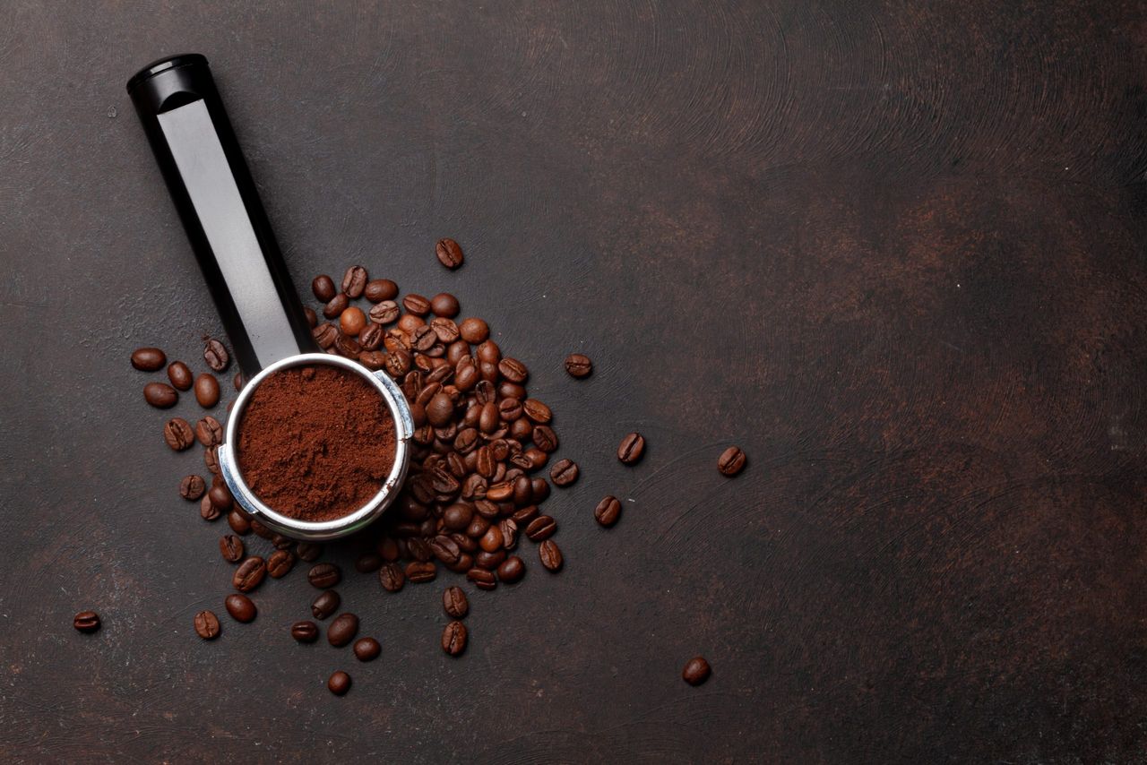 Roasted coffee beans and ground coffee in filter holder. Top view flat lay with copy space