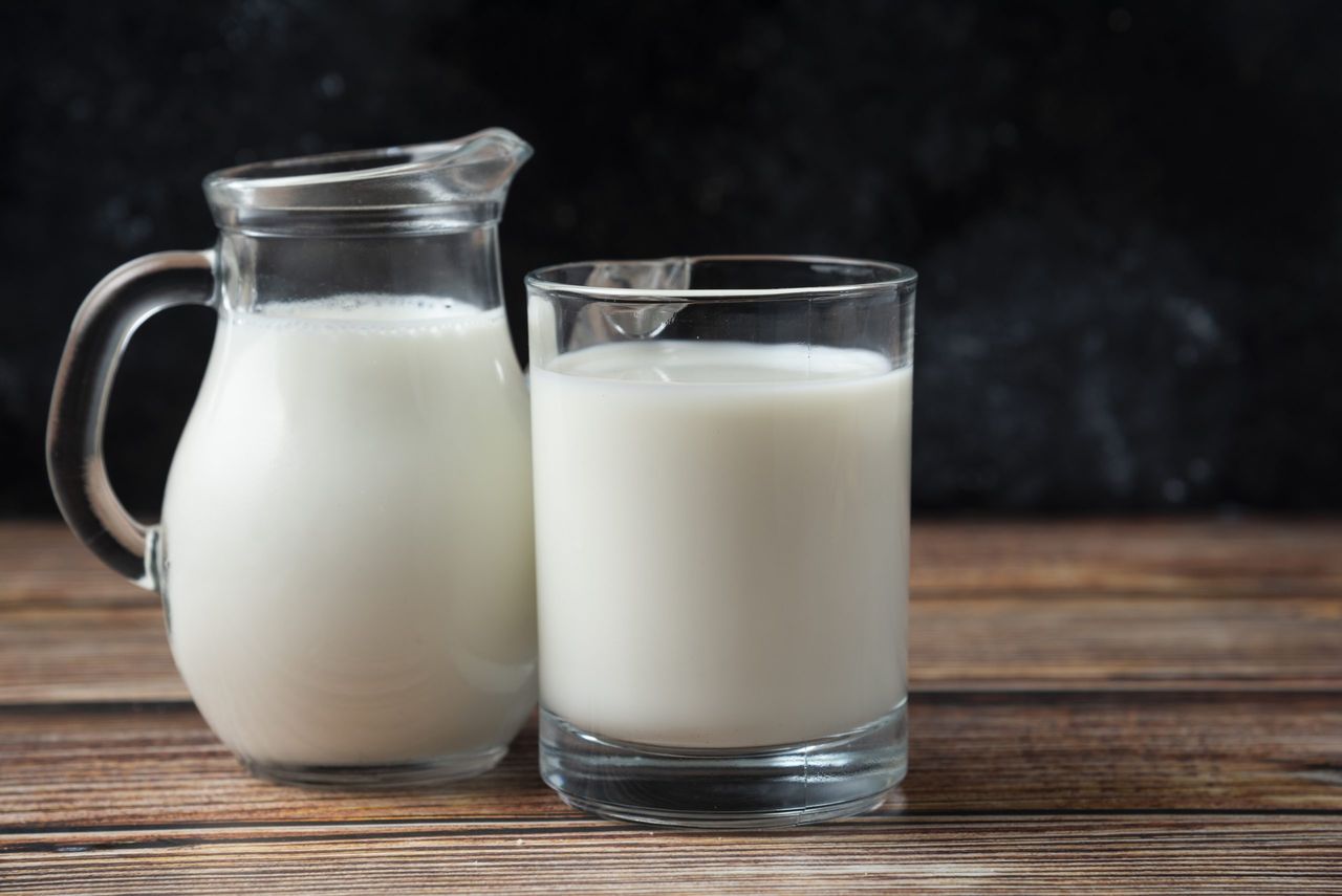 Fresh milk in a mug and jug on wooden table. High quality photo