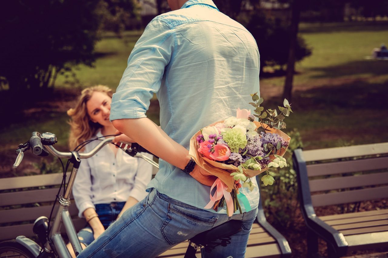 Surprise flower bouquet from casual man on a bicycle to cute blond woman.