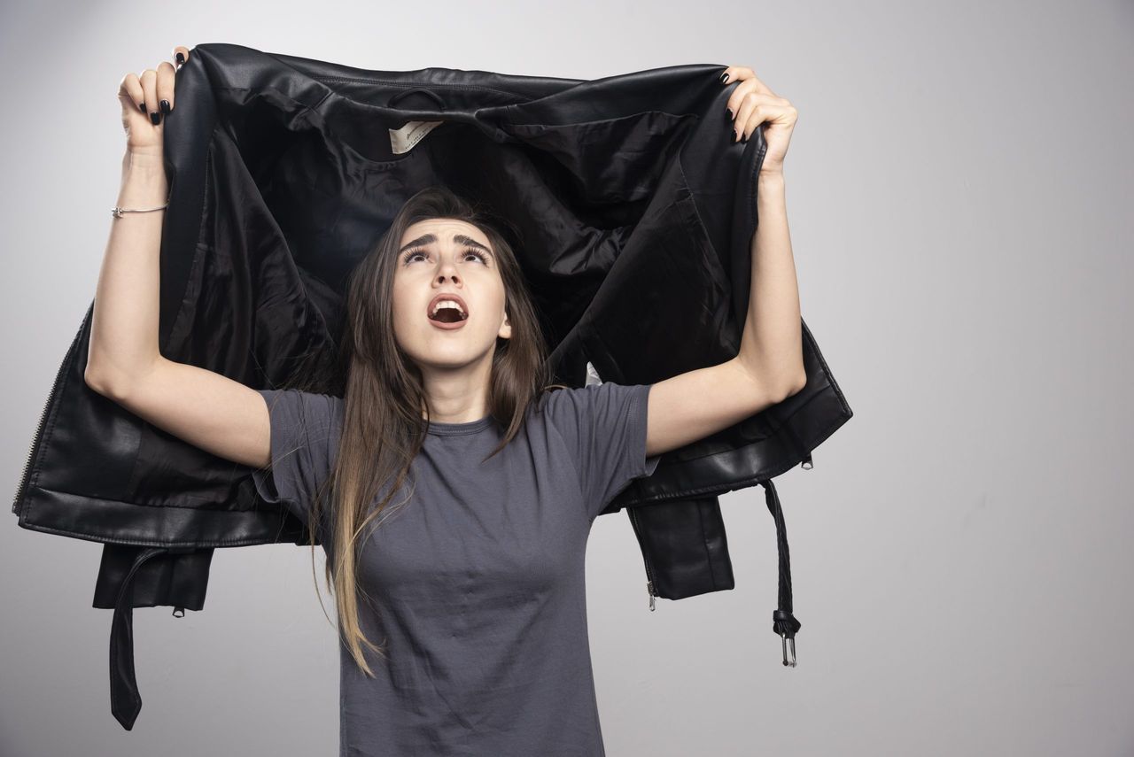 Model looking at her black leather jacket over a gray background. High quality photo