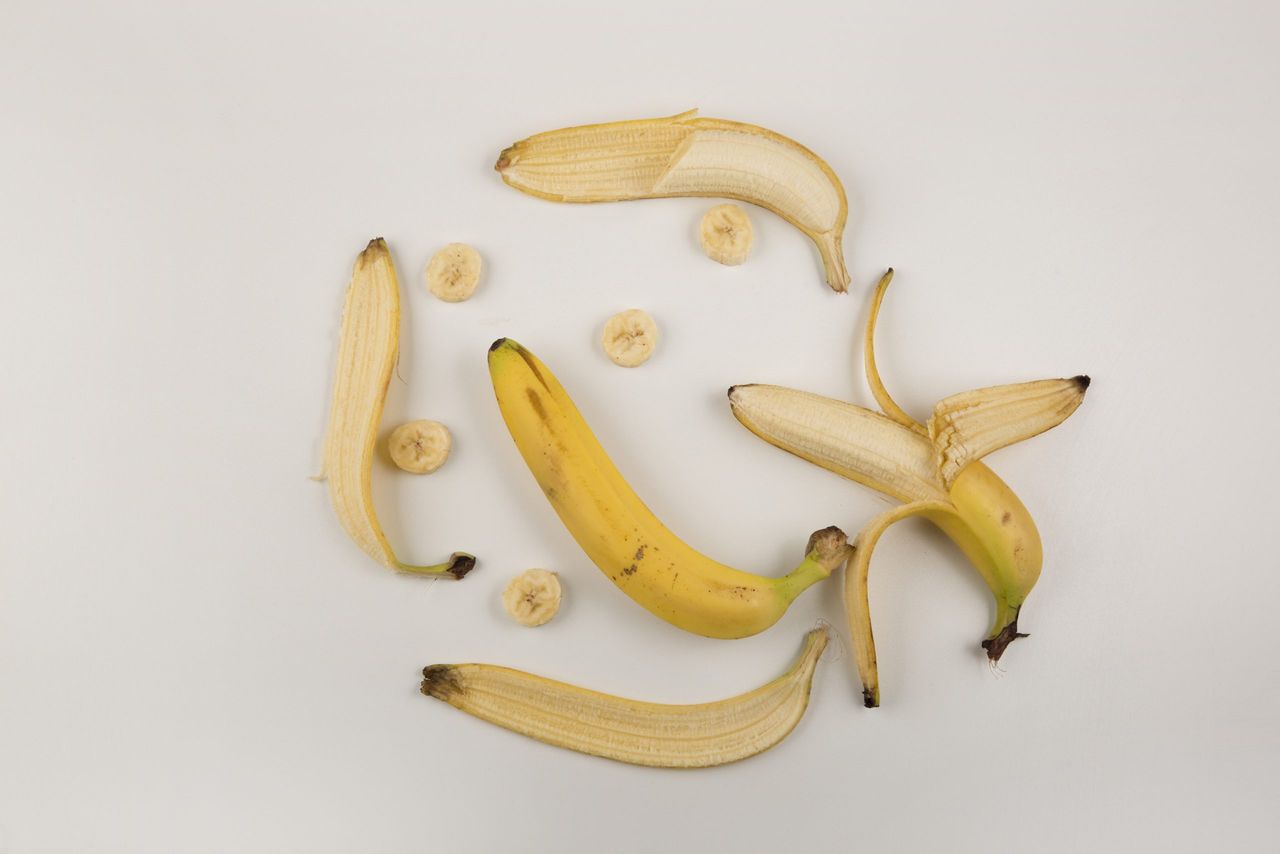 Peeled and sliced bananas on white background, top view. High quality photo