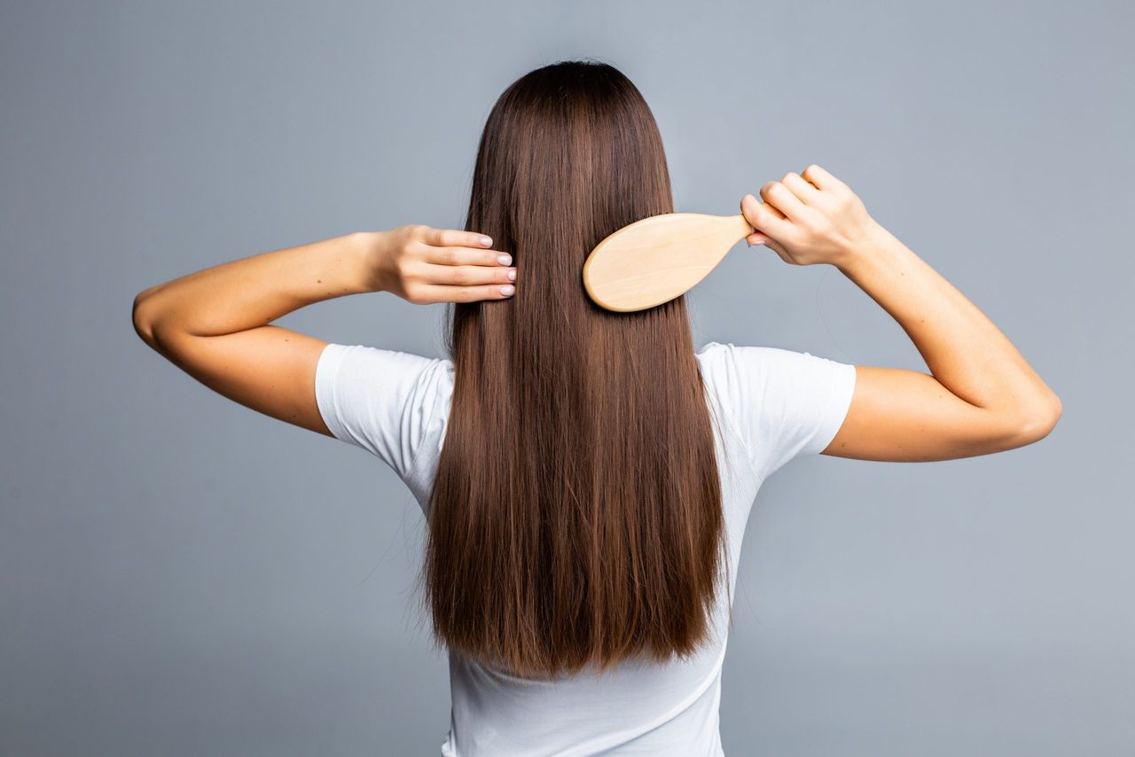 Combing healthy long straight female hair - close-up