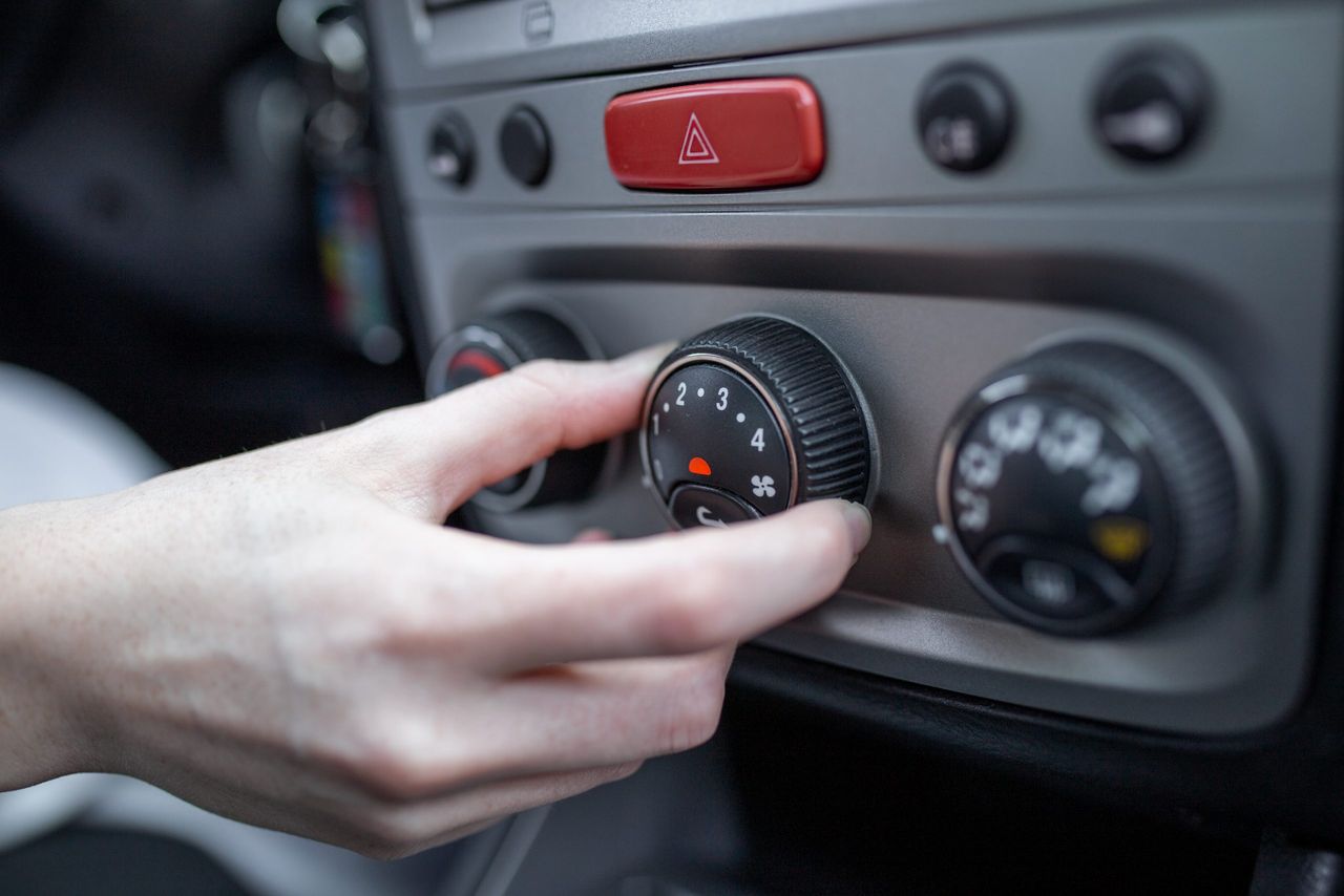 Woman hand turning on car air conditioning system, car air conditioner on off button close up view