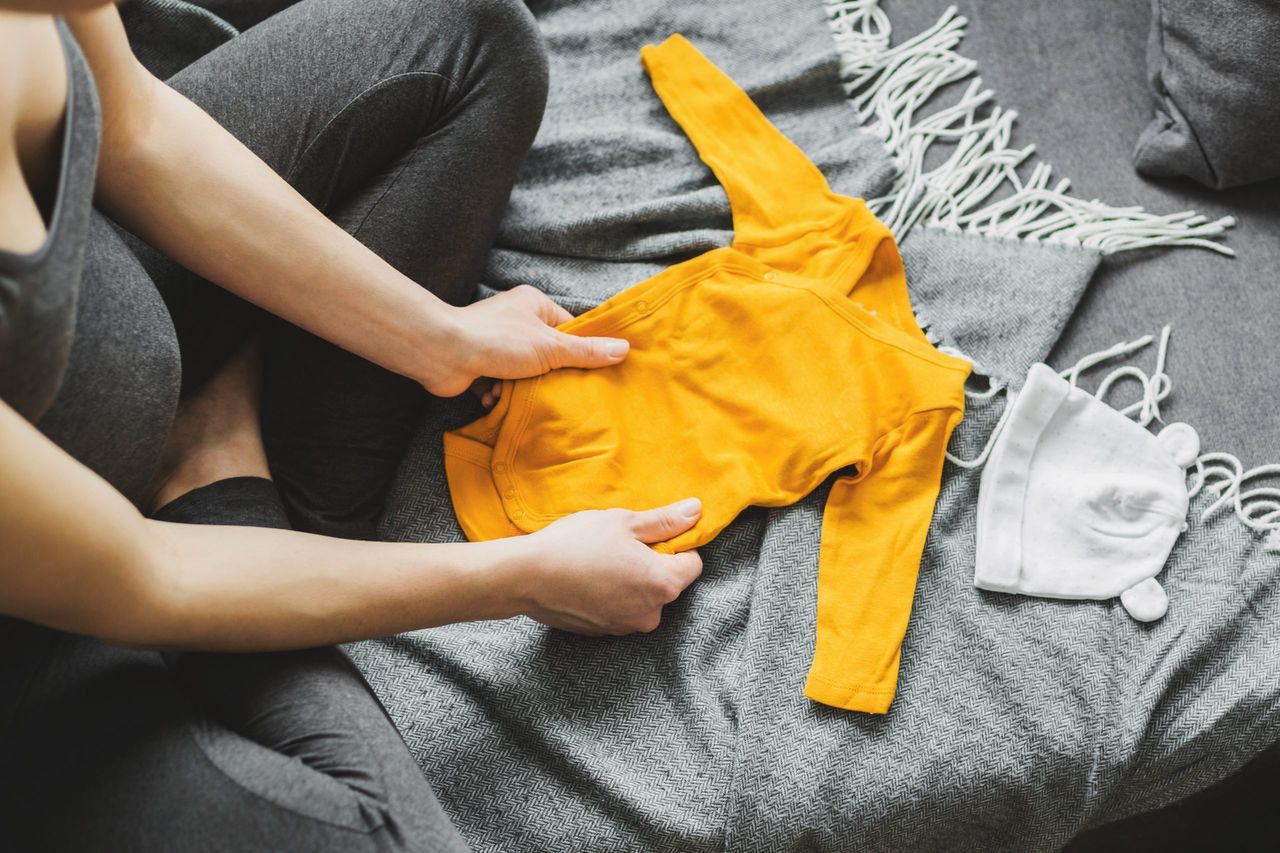 Young pregnant woman preparing baby clothes. Lifestyle. Baby family pregnancy concept.