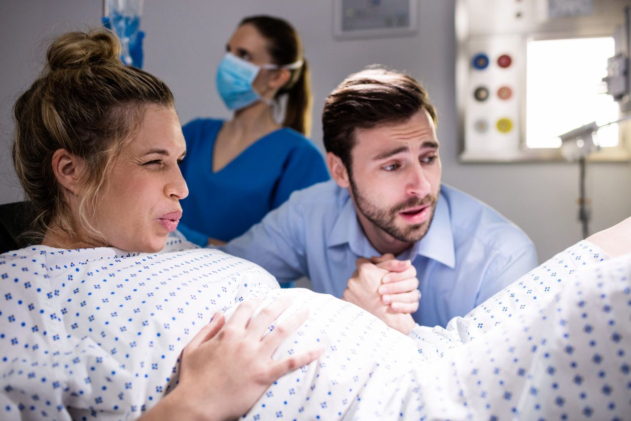Man comforting pregnant woman during labor at hospital