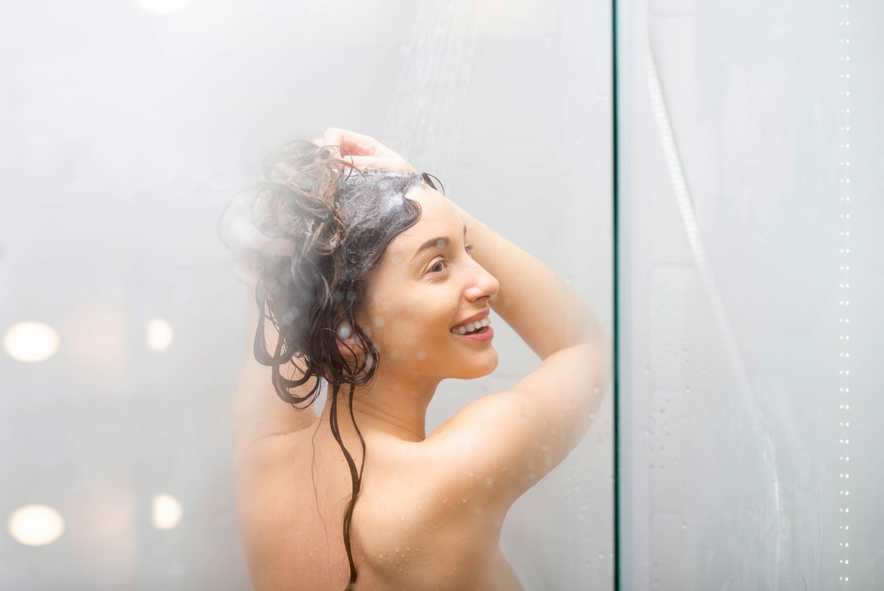 Young woman washing hair with shanpoo in the shower. Hair care