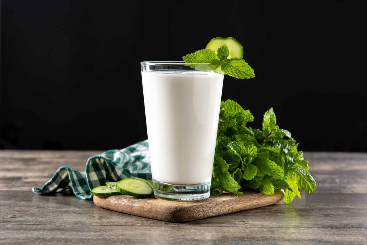 Ayran drink with mint and cucumber in glass on wooden table