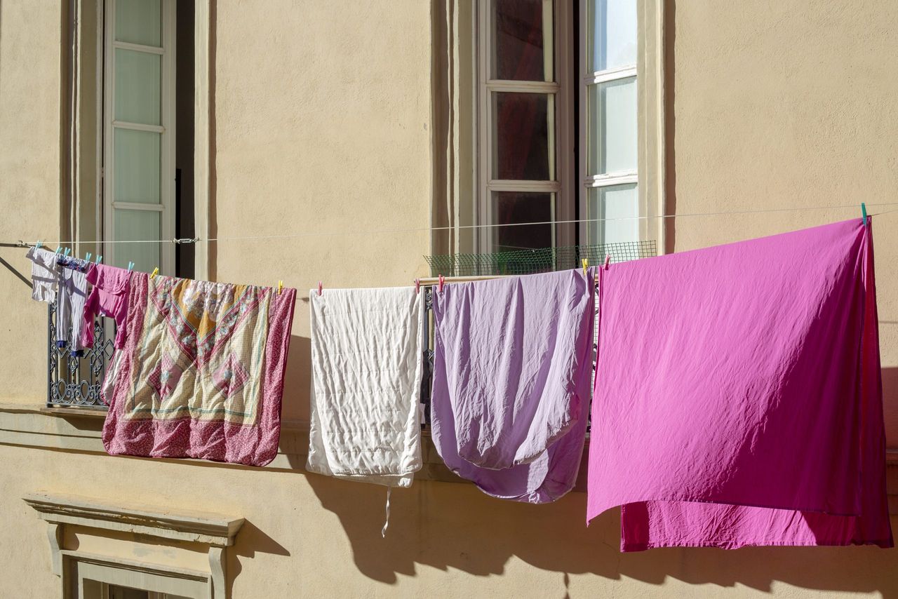 Clothes and sheets hanging on a balcony drying in the sun