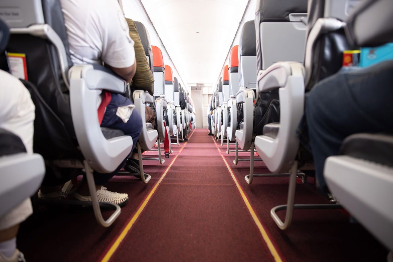 View of Airplane Aisle  with the Passengers Sitting on their Seats