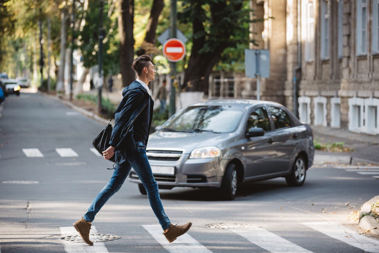 Young man cross the street at a crosswalk