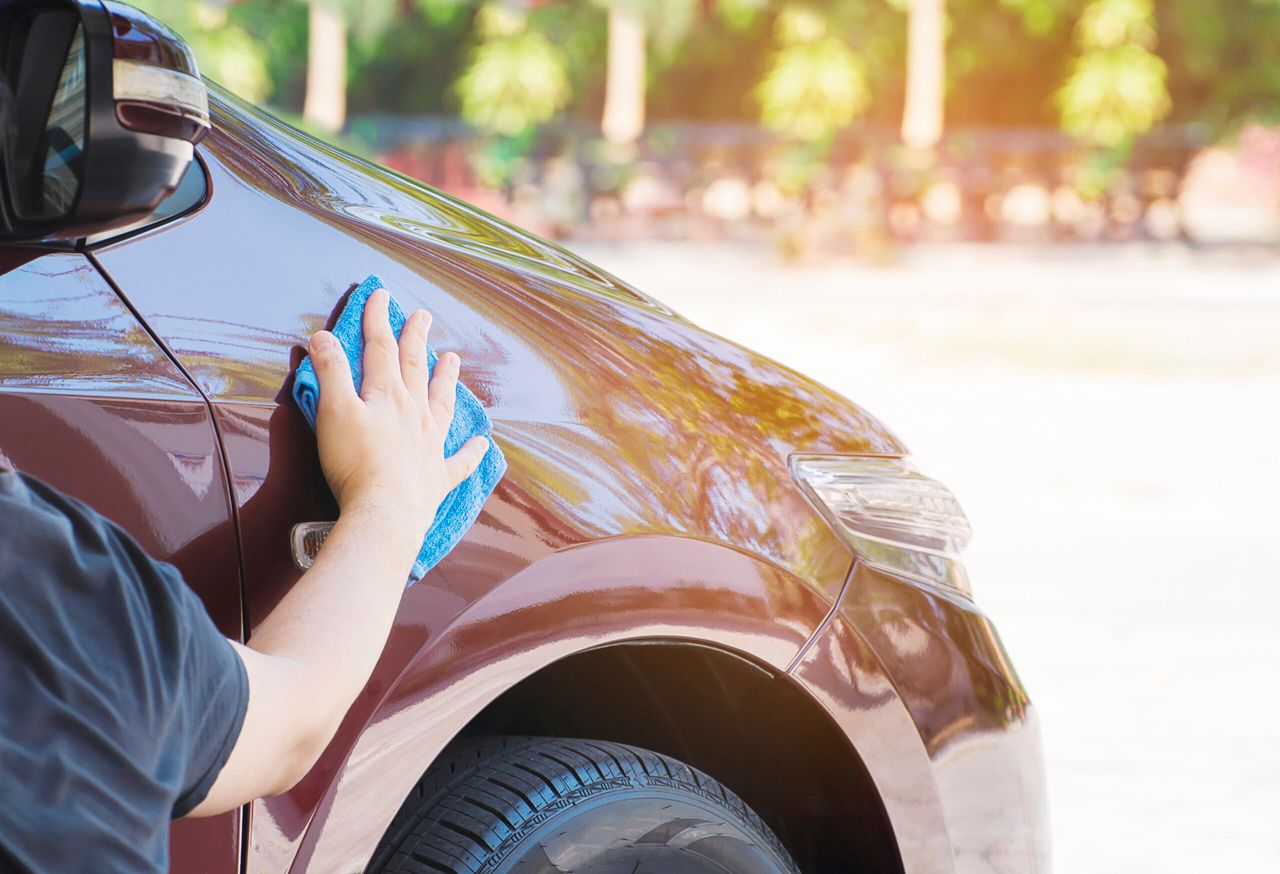 Man's hand is cleaning and waxing the car