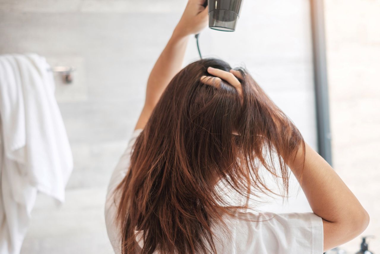 young woman using hair dryer at home or hotel. Hairstyles and lifestyle concepts