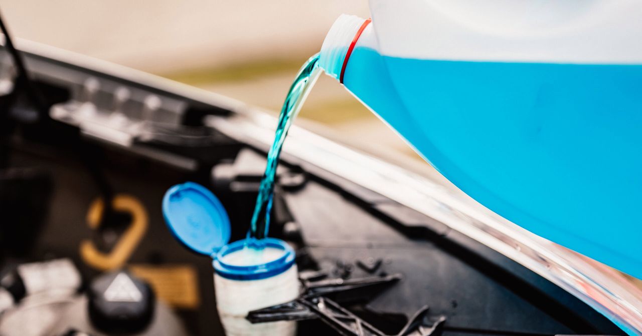 Pouring antifreeze. Filling a windshield washer tank with an antifreeze in winter cold weather.