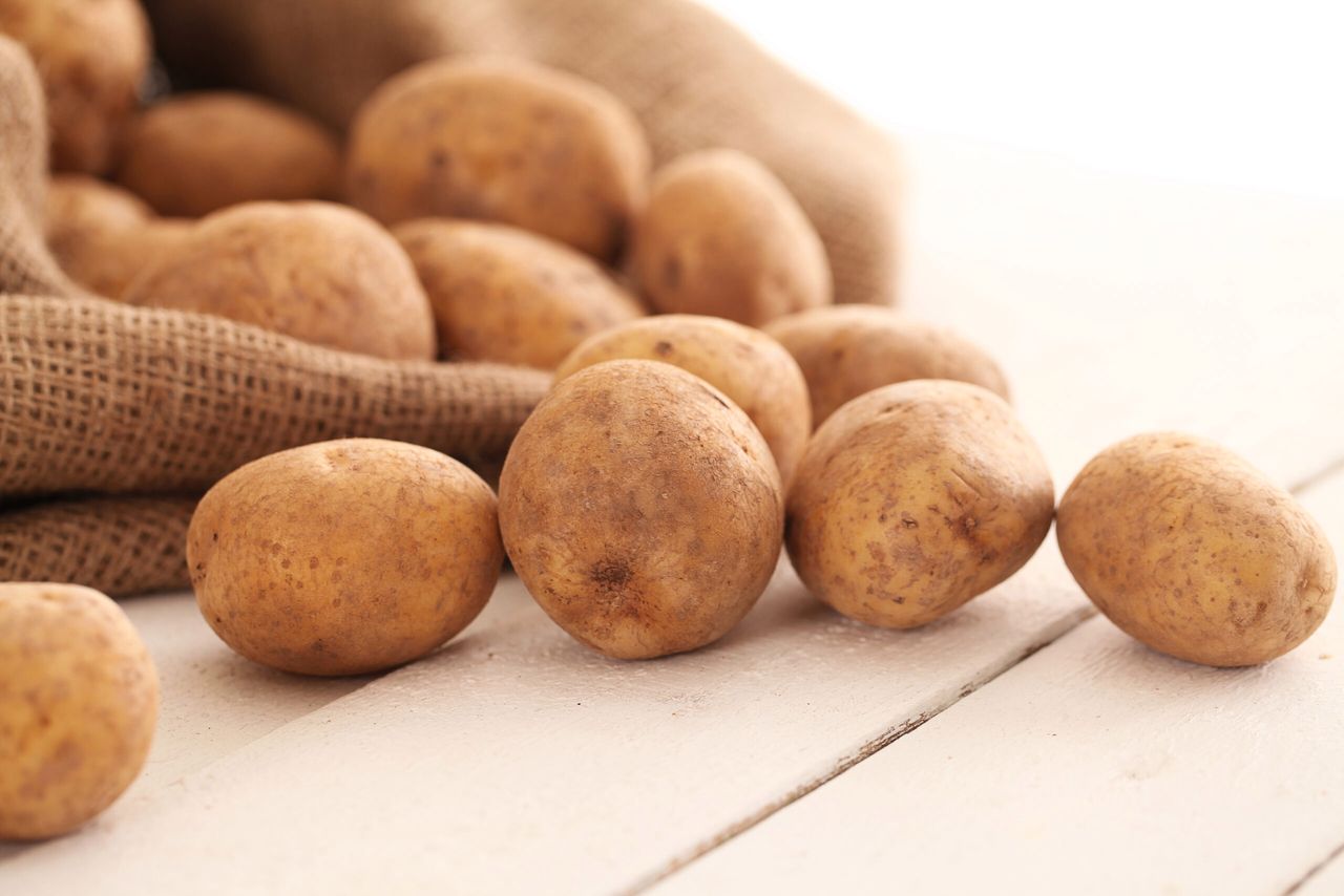 Rustic fresh unpeeled potatoes on a white wooden table