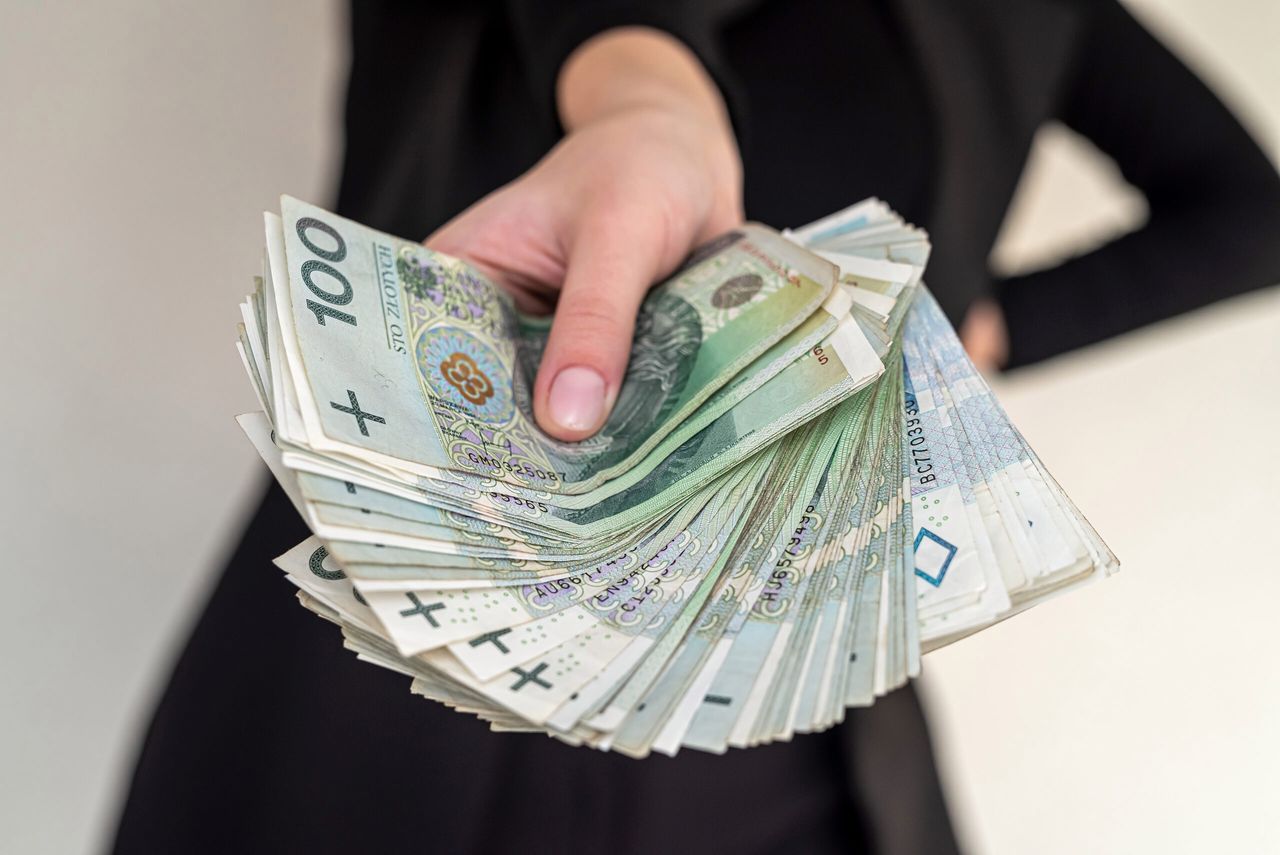 close up of several banknotes denomination of 100 zlotys Polish money zlotys holding a fan in the form of a woman in a suit. The concept of zlotys in women's hands