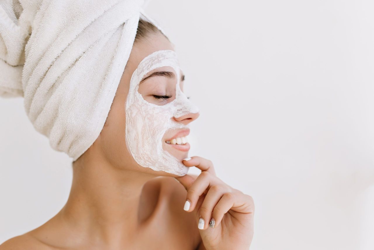 Close-up portrait of beautiful young woman smiling with towels after take bath make cosmetic mask on her face. Rejuvenation, cosmetology, spa, hydration and care face. Clea,perfect skin.Place for text