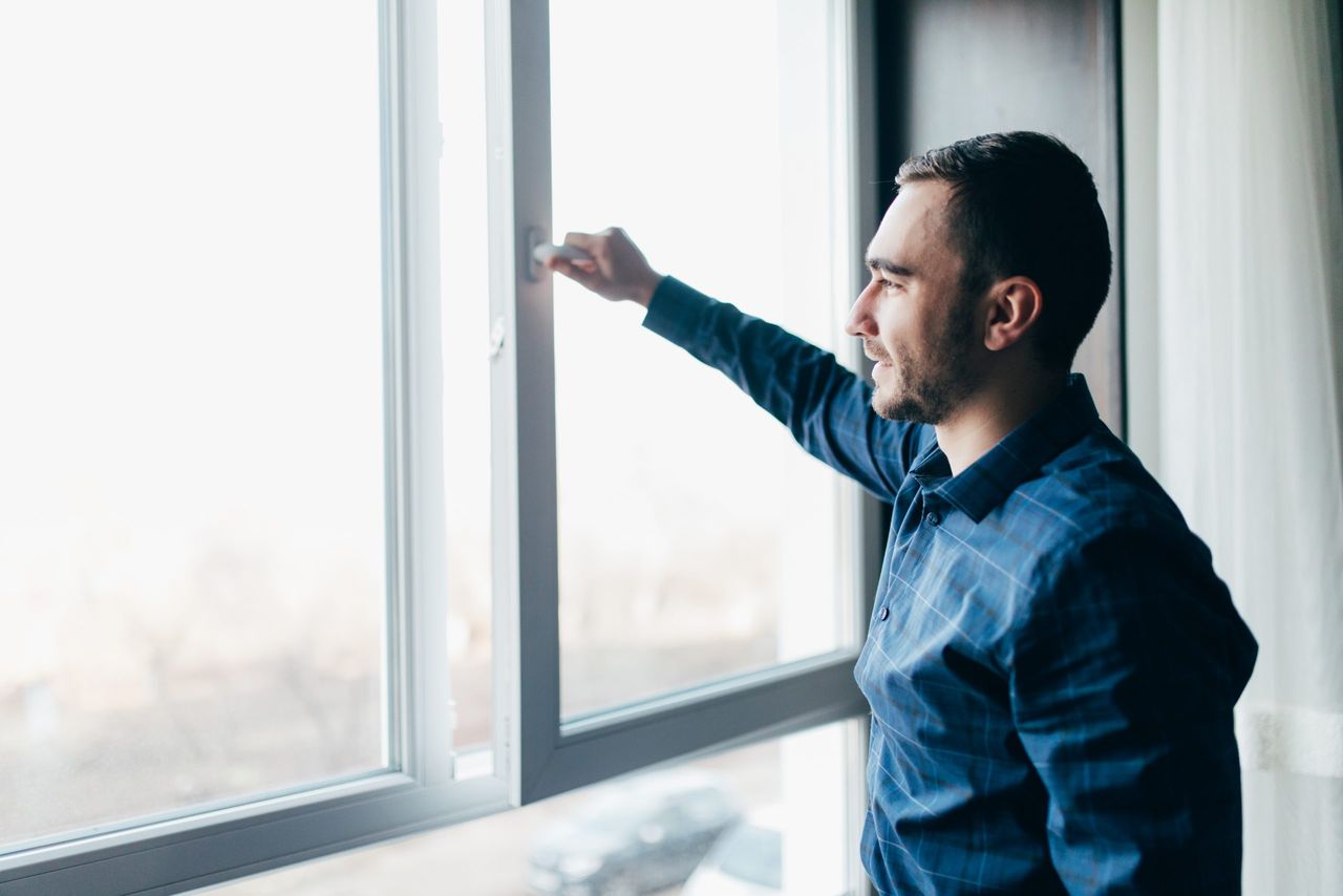 Man is opening the window at home to refresh the room