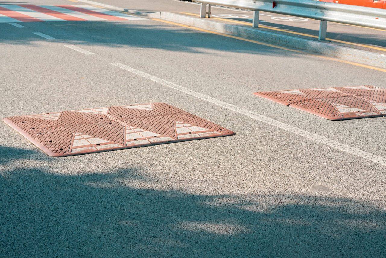 Brown rectangular speed bumps installed on the road. Nobody. Roadblock. Control. Direction. Slow. Way. Device. Motion. Police Officer. Sleeping. Sign. Policeman. Caution. Crossing