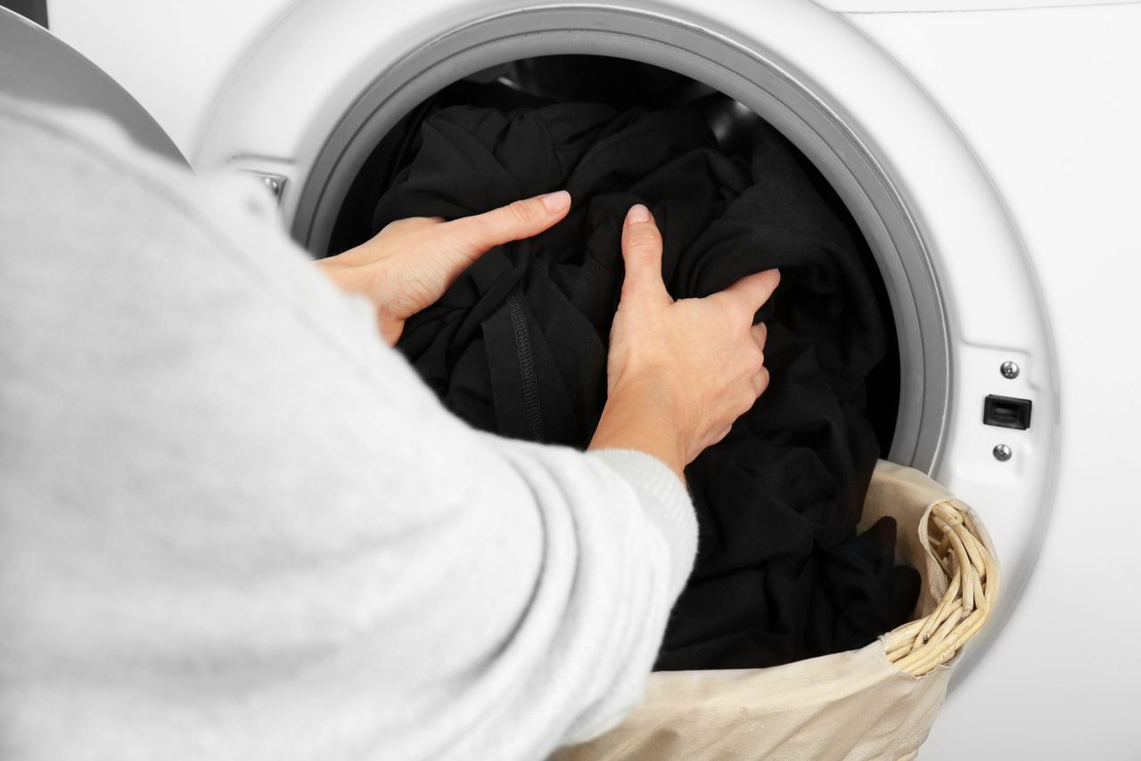 Female hands getting out clean clothes from washing machine