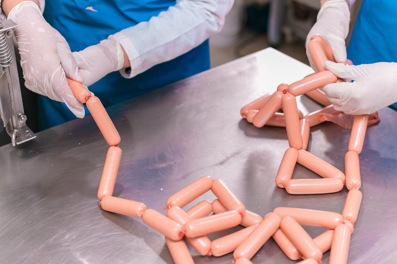 Employees sorting produced meat sausages. High quality photo