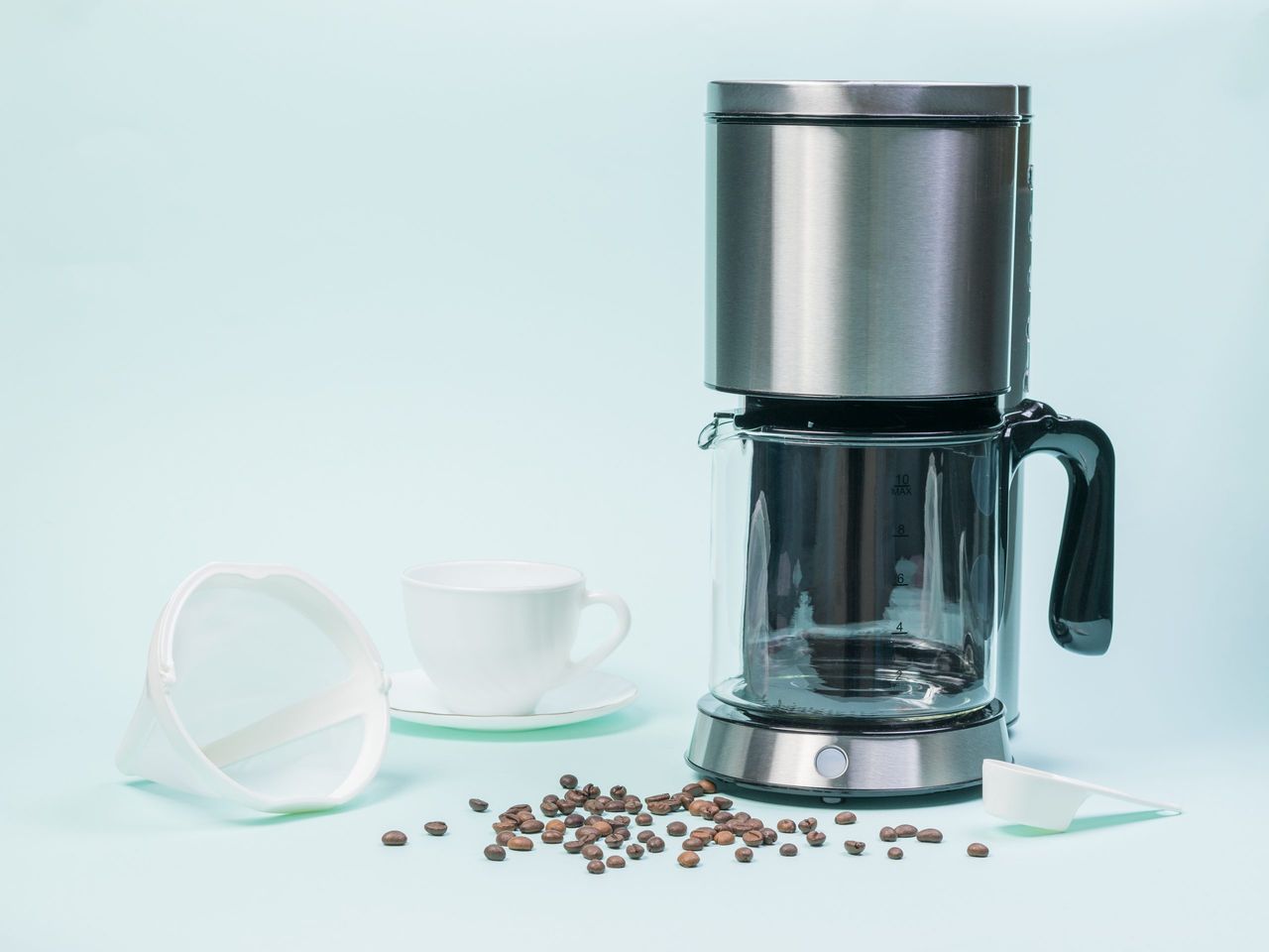 Coffee maker, Cup, strainer and coffee beans on a white table. The concept of a classic Breakfast.