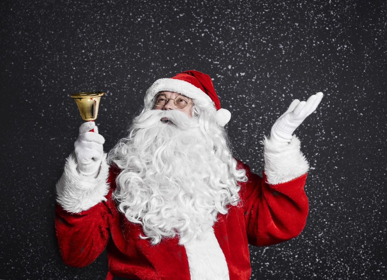 Santa claus with handbell among snow falling