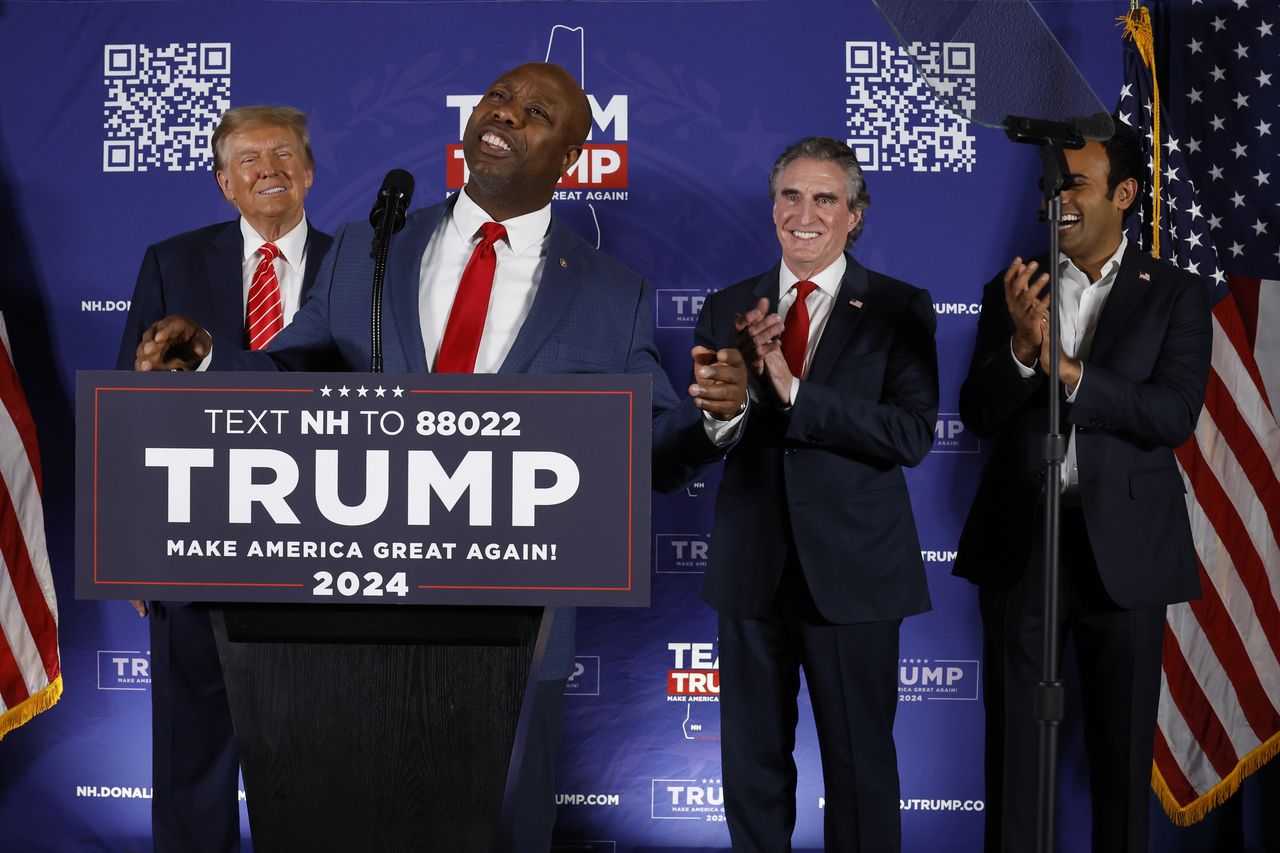 LACONIA, NEW HAMPSHIRE - JANUARY 22: Sen. Tim Scott (R-SC) (2nd-R) speaks as Republican presidential candidate and former President Donald Trump (L), North Dakota Governor Doug Burgum (2nd-R) and Vivek Ramaswamy (R) listen during a campaign rally in the basement ballroom of The Margate Resort on January 22, 2024 in Laconia, New Hampshire. Ramaswamy, Burgum and Scott all ran against Trump for the Republican presidential nomination but later dropped out and endorsed him. Trump is rallying supporters the day before New Hampshire voters will weigh in on the Republican nominating race with the first-in-the-nation primary. (Photo by Chip Somodevilla/Getty Images)