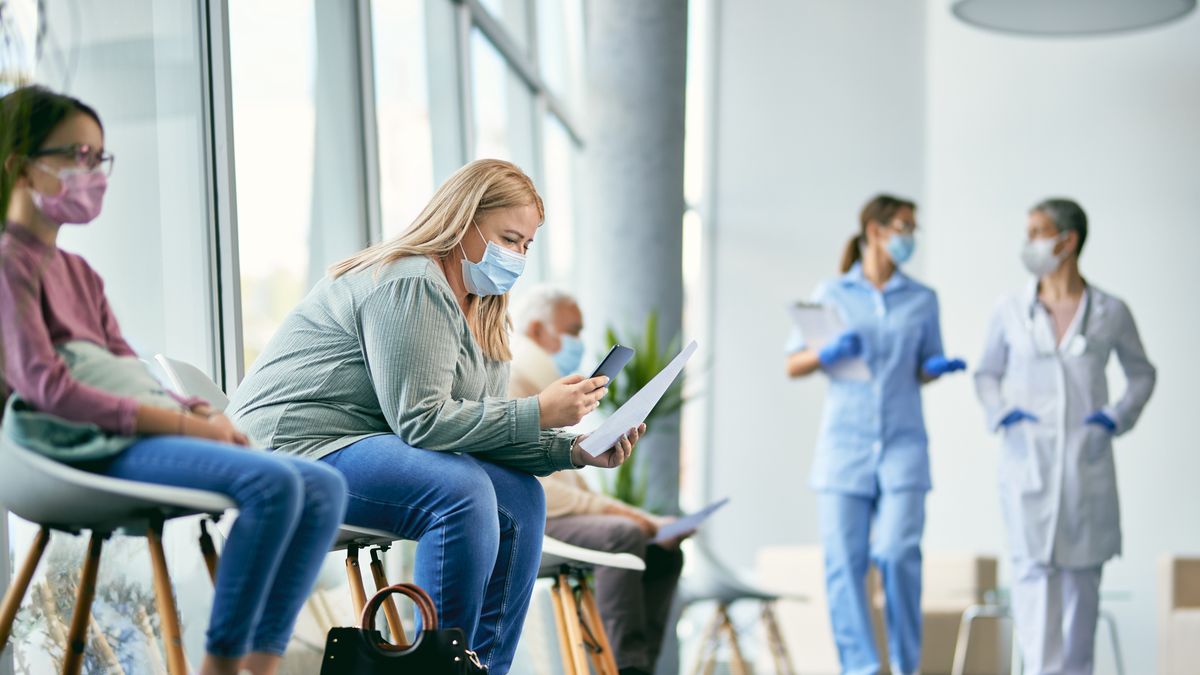 Woman with face mask using smart phone while reading her medical report in waiting room at the clinic.
Female patient examining medical paperwork and using mobile phone while sitting in hallway at the hospital.
Drazen Zigic