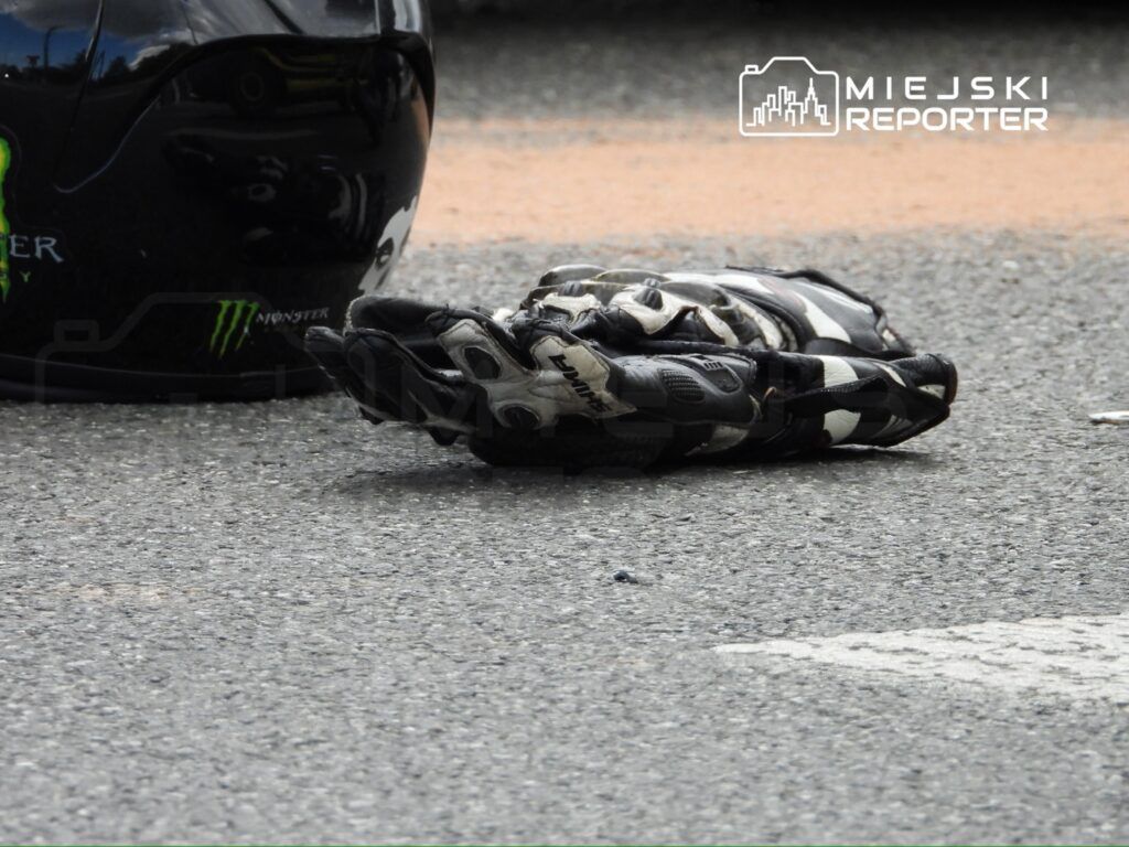 Czarny kask i rękawica motocyklowa leżące na asfaltowej nawierzchni.